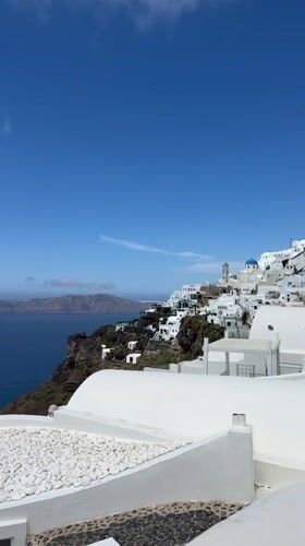 Clear skies frame Santorini's whitewashed buildings in morning view