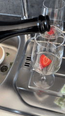 Person enjoys strawberry-garnished wine on deck in Kiel