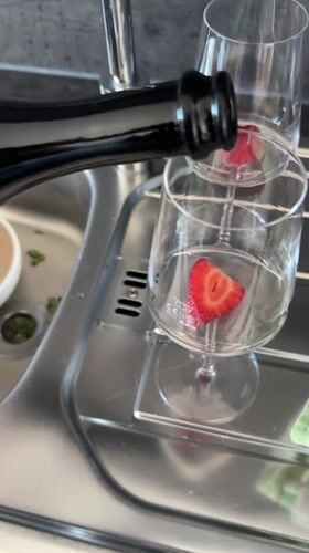 Person enjoys strawberry-garnished wine on deck in Kiel