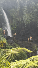 Tourists enjoy swimming at tropical waterfall in Susut, Indonesia