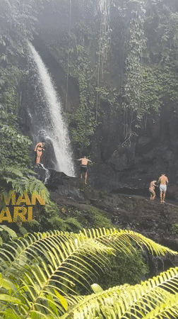 Tourists enjoy swimming at tropical waterfall in Susut, Indonesia