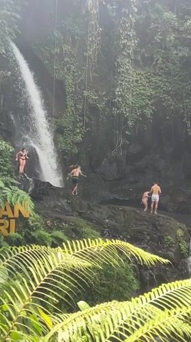 Tourists enjoy swimming at tropical waterfall in Susut, Indonesia