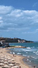 A sunny beach day with swimmers, rocks, and rolling waves