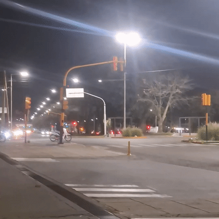 Motorcycles navigate nighttime intersection in Sarandí, Argentina