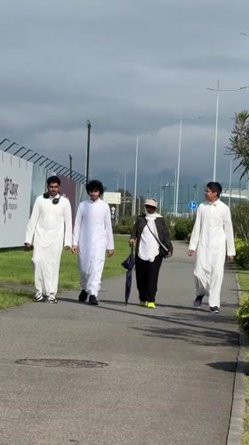Four people walk paved path in traditional clothing, Sirius Russia