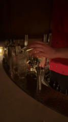 Bartender serves drinks at candlelit NYC bar during early morning