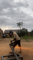 Man performs metal cutting work in Nigerian village yard