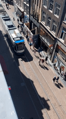 Tram 24 travels busy Amsterdam street on sunny afternoon