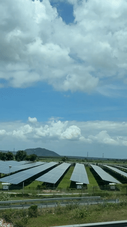 Solar farm sprawls across open grassland near Vietnamese mountains