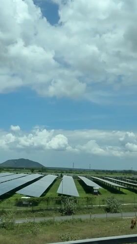 Solar farm sprawls across open grassland near Vietnamese mountains