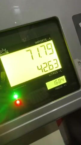 The video shows a close-up of a gas pump display screen. The screen shows the increasing amount of money and liters of fuel being dispensed. The "Importe" (amount) goes up in Euros. The "Litros" (liters) amount is also increasing. The price per liter is displayed as 1.684. The gas pump is a "Petrotex" brand. There are red and green indicator lights on the pump.