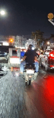 Scooter rider with blue lights travels wet Lhokseumawe streets