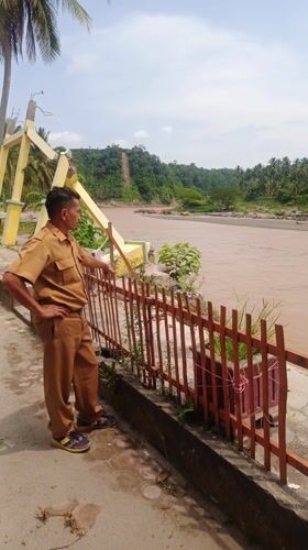 Damaged monument, uniformed observer documented in Simpangjaya riverside scene