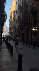 Person walks European street, photographed near graffiti mural