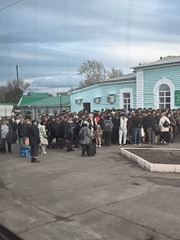 Travelers gather with luggage outside building in Sol-Iletsk, Russia