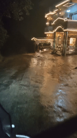 Floodwater reaches decorated building entrance in Vashisht at night