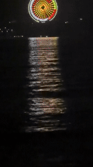 Lit Ferris wheel reflects across water in Nha Trang