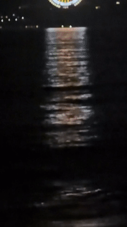 Lit Ferris wheel reflects across water in Nha Trang