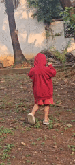 Kid roams a Bekasi yard, crossing paths with chickens and a cat
