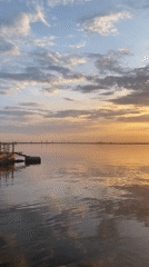 Woman enjoys golden sunset by water in Chaikovsky, Russia
