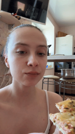 Woman enjoys pizza breakfast with cats in Russian home