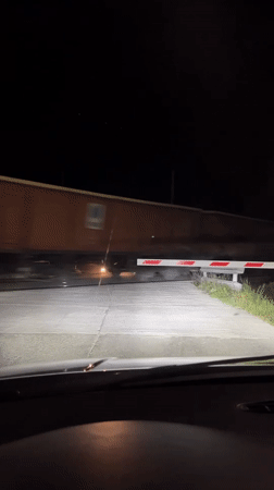 Train crosses road at night in Anevo, Bulgaria