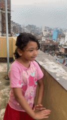 Rooftop afternoon in Dhaka, plants, dancing, flooded streets below