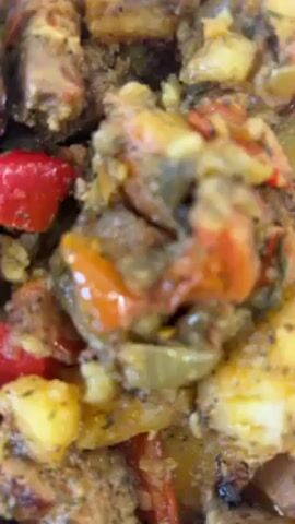 The video shows a close-up of a plate of food. The food appears to be a mix of potatoes, red peppers, and meat. The dish is seasoned with herbs. A fork is visible on the plate. The plate is on a white surface.
