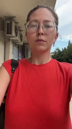 Woman in red walks through Podgorica carrying black purse