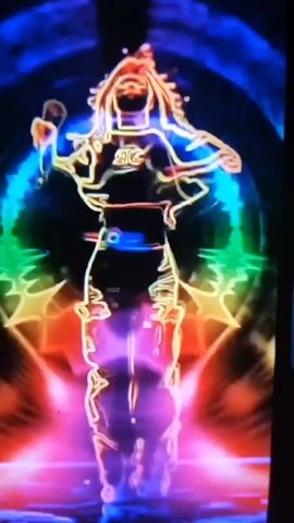 A person's silhouette is outlined in neon colors against a dark background. The silhouette is animated, appearing to dance or perform. Around the silhouette, there are abstract shapes and colors that pulse and shift, creating a vibrant and energetic visual effect. The colors used are predominantly blues, purples, reds, oranges, and yellows, with some green and yellow accents.
