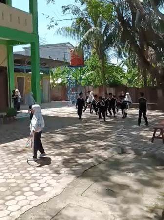 Children in uniforms play with hula hoops in Lhokseumawe