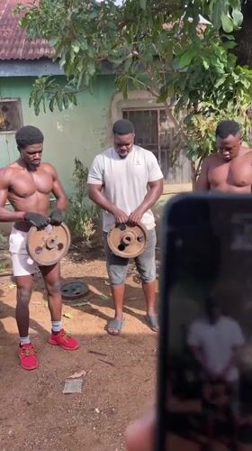 Three men hold weight plates in Akwanga yard