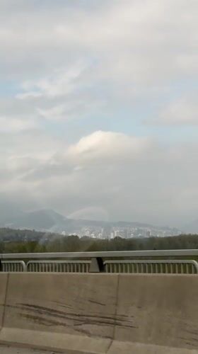 Vehicle travels bridge in Coquitlam with city view