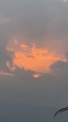 Orange sunset through gray clouds captured in Pokhara, Nepal