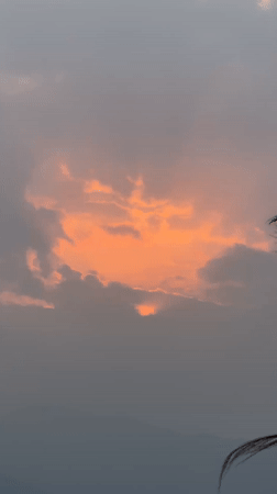 Orange sunset through gray clouds captured in Pokhara, Nepal