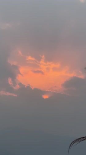Orange sunset through gray clouds captured in Pokhara, Nepal