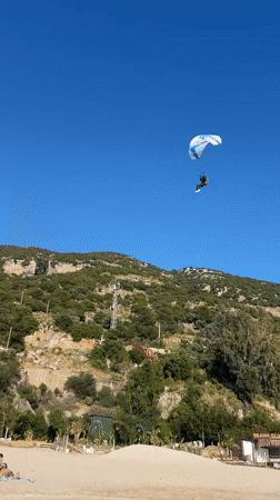 Paragliders soar over Fethiye beach as visitors enjoy clear skies