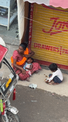 Resting beside a shuttered Delhi shop with two small children