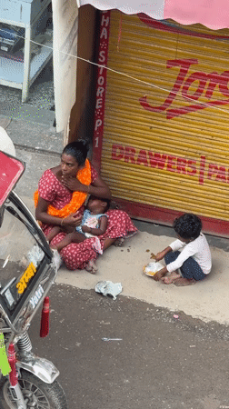 Resting beside a shuttered Delhi shop with two small children