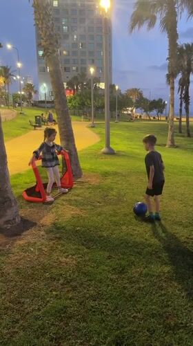 Children play evening soccer in Netanya park at dusk
