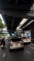 Bangkok traffic pause under an elevated road, Grab rider in queue