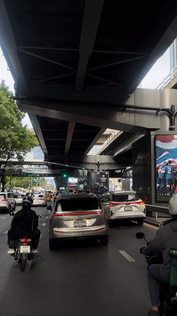Bangkok traffic pause under an elevated road, Grab rider in queue