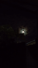 Person reaches toward full moon on cloudy night