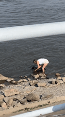 Cooling off with a black dog at a rocky Khabarovsk shoreline