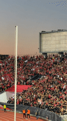 Red and black fans fill a Sofia stadium at dusk