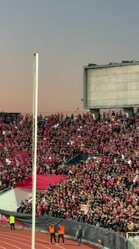 Red and black fans fill a Sofia stadium at dusk