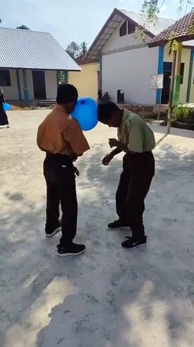 Blue balloon forehead game between two kids in school uniforms