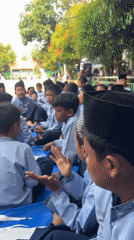 Students in uniform seated on a tarp at outdoor Gelam Jaya assembly