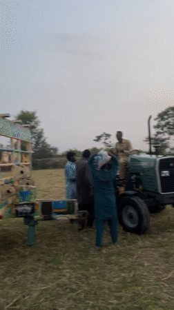 Farm workers harvest grain with tractors in Parwanwala Pakistan