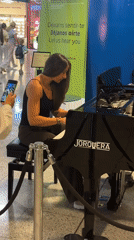 Woman plays piano performance at Barcelona airport terminal